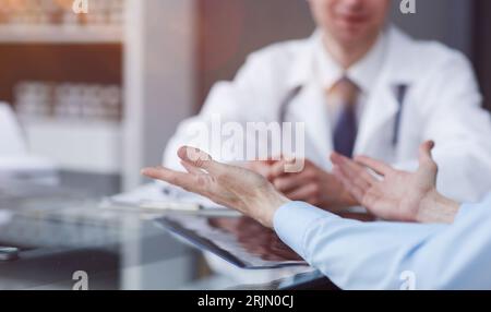 Una foto ravvicinata delle mani di una paziente che sta gestendo vicino ad un medico durante un appuntamento in un ospedale. Foto Stock