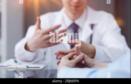 Una foto ravvicinata delle mani di una paziente che sta gestendo vicino ad un medico durante un appuntamento in un ospedale. Foto Stock