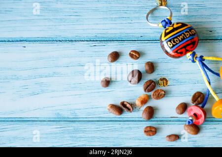 Uno sfondo blu con una collezione di chicchi di caffè colombiani, souvenir e bandiera colombiana. Foto Stock