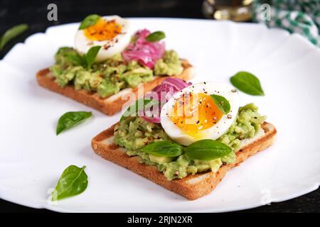 Toast salutari con pestello di avocado, uova sode, spezie e cipolle rosse. Deliziosa colazione o spuntino. Foto Stock