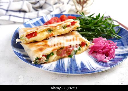 Gustosa colazione con quesadilla e uova. Cucina messicana. Cibo di tendenza con pita, omelette, formaggio, pomodori Foto Stock