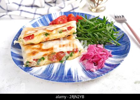 Gustosa colazione con quesadilla e uova. Cucina messicana. Cibo di tendenza con pita, omelette, formaggio, pomodori Foto Stock