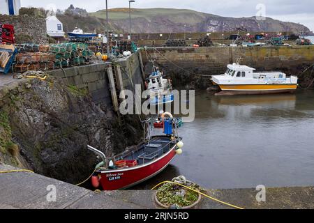 St Abbs, Berwickshire, Scozia, Regno Unito. 28 marzo 2023. Con la bassa marea, le barche da pesca ormeggiavano nel porto di St Abbs Foto Stock