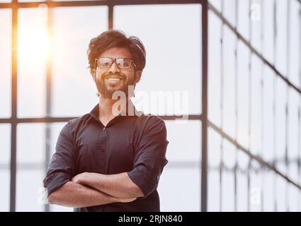 Un giovane di successo ha incrociato le braccia. Elegante uomo d'affari in camicia casual. Foto Stock