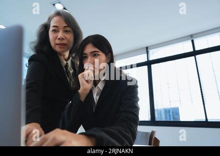 Senior manager della collaborazione per il lavoro di squadra che spiega a un tirocinante per la formazione digitale Foto Stock