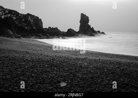 Un idilliaco scenario balneare a Reykjavik, Islanda, caratterizzato da sabbia nera e nebbia Foto Stock