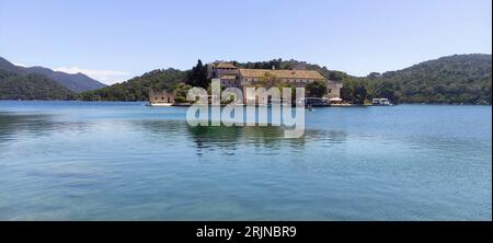 Una montagna maestosa con un grande edificio arroccato sulla cima vicino a un lago tranquillo, che offre uno sfondo mozzafiato per qualsiasi scena Foto Stock