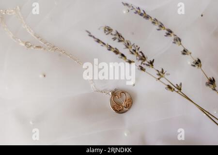 Primo piano di una collana dorata su uno sfondo bianco decorato con fiori Foto Stock