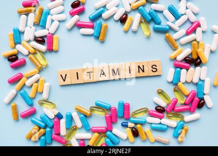 Il concetto di salute e assistenza sanitaria. Luminoso diversi tipi di farmaci per la salute. Medicinali su sfondo blu con l'iscrizione vitamine Foto Stock