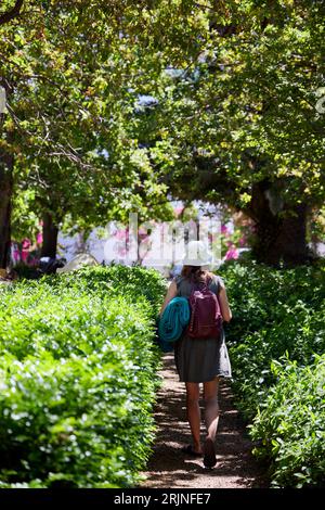 Una donna che cammina lungo un sentiero panoramico con uno zaino sulla schiena Foto Stock