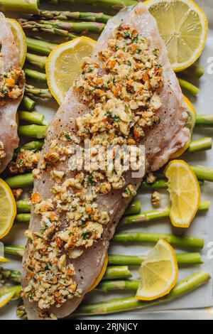 Pesce rosa del pacifico crudo su un letto di asparagi, mole di limone con burro marrone mandorle e prezzemolo, cena in padella. Foto Stock