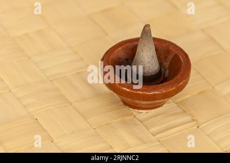 Primo piano di un incenso a forma conica in una piccola ciotola di terracotta Foto Stock