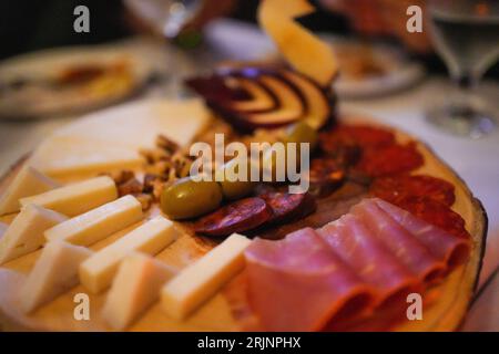 Un appetitoso piatto di piatti assortiti, tra cui una varietà di formaggi, salumi e olive Foto Stock