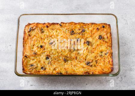 Piatto da forno in vetro con gratin di patate appena sfornate, torta o casseruola su sfondo grigio testurizzato, vista dall'alto Foto Stock