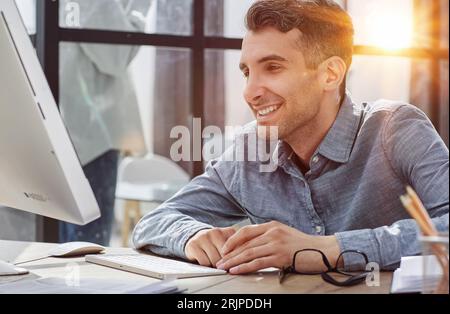 Uomo d'affari stanco che dorme sulla sua scrivania di fronte al computer portatile, lavora troppo, si sente esausto in un ufficio moderno. Foto Stock