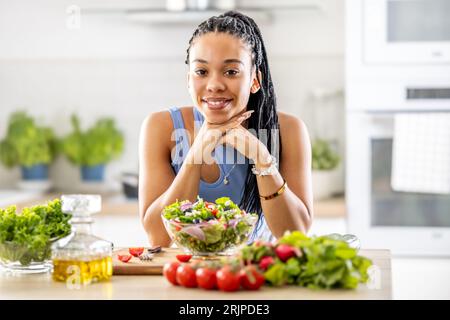 Una bella ragazza afro-americana ha preparato una sana insalata mista di verdure fresche. Foto Stock