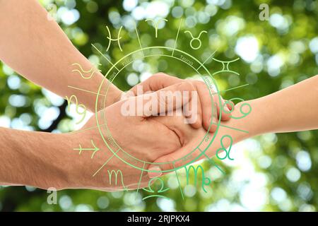 Relazioni e oroscopo. Ruota zodiacale e foto di uomo e donna che si tengono per mano all'aperto, primo piano Foto Stock