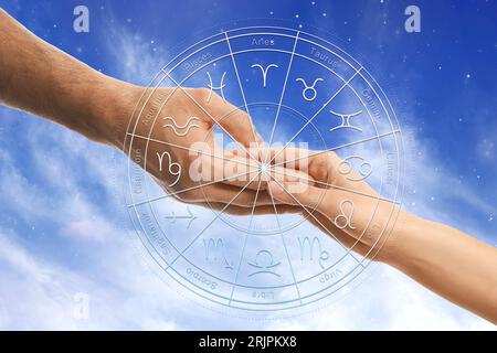 Relazioni e oroscopo. Ruota zodiacale e foto di uomo e donna che si tengono per mano contro il cielo, primo piano Foto Stock