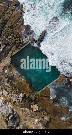 Una vista aerea di una serena e tranquilla piscina in una baia oceanica circondata da grandi scogliere rocciose: Mahon Pool, Maroubra, Sydney, Australia Foto Stock