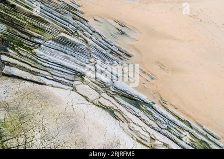 Flysch sepolto nella sabbia di una spiaggia, bellissimo sfondo geologico. Foto Stock