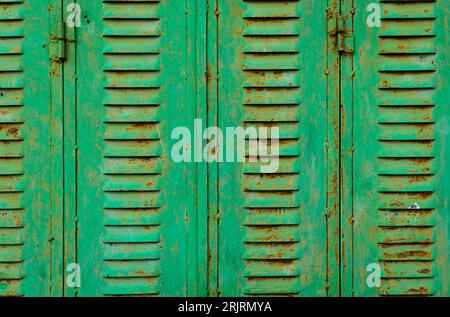 Vista di una vecchia finestra in metallo con colore verde e macchie di ruggine. Sfondi concettuali, modelli, trame, risorse grafiche. Foto Stock