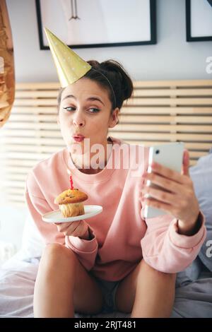 Donna soffia sulla candelina della torta di compleanno e facendo un selfie Foto Stock