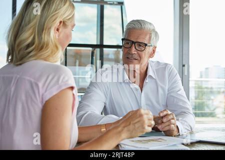 Imprenditore snd donna seduta in ufficio, discutendo di progetto Foto Stock