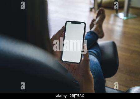 Giovane donna utilizza lo smartphone a casa Foto Stock