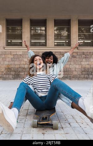 Madre e figlia si divertono insieme seduti sullo skateboard Foto Stock