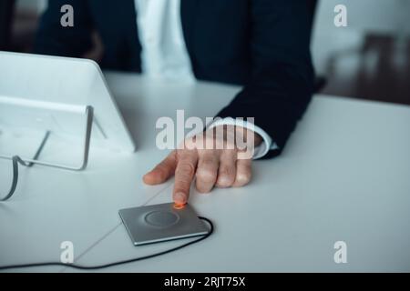 Mano di un uomo d'affari che preme il pulsante alla scrivania Foto Stock