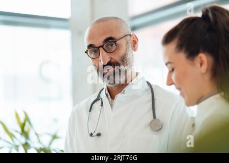 Medico maturo con collega sorridente in ospedale Foto Stock