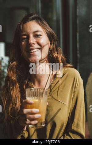 Giovane donna sorridente che regge un bicchiere di succo Foto Stock
