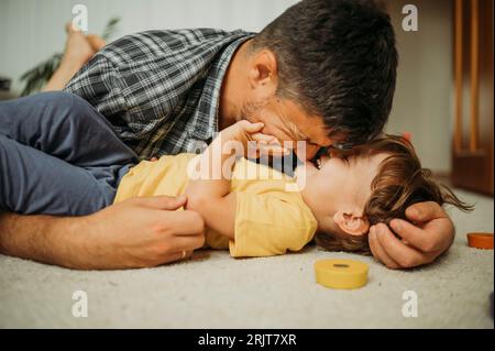 Padre sorridente che trascorre il tempo libero giocando a casa Foto Stock