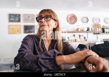 Premuroso proprietario di un caffè seduto nella caffetteria Foto Stock
