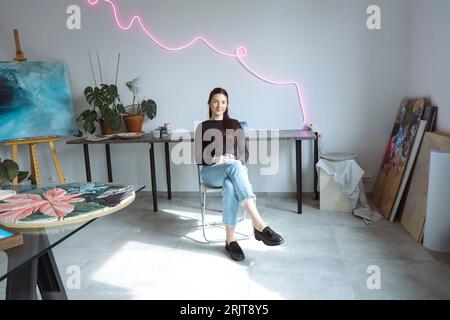 Giovane artista seduto sulla sedia dello studio Foto Stock
