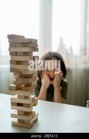 Ragazzo che guarda la torre di Jenga sul tavolo a casa Foto Stock