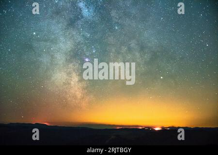 La via Lattea illumina il cielo notturno sugli incendi boschivi nel North Cascades National Park, Washington, USA Foto Stock