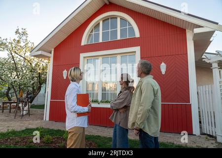 Agente immobiliare e coppia che guardano casa Foto Stock