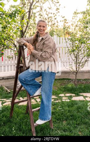 Donna matura sorridente in piedi sulla scala Foto Stock