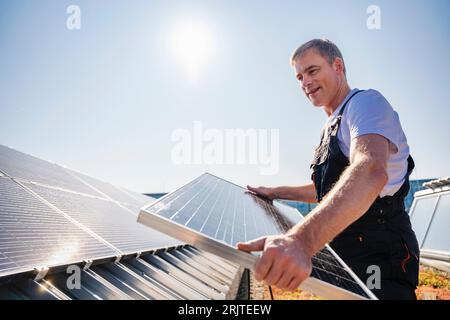 Artigiano che installa pannelli solari sul tetto di un edificio aziendale Foto Stock