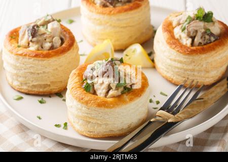 Delizioso classico vol-au-vent ripieno di pollo, funghi in una salsa cremosa da vicino in un piatto sul tavolo. orizzontale Foto Stock