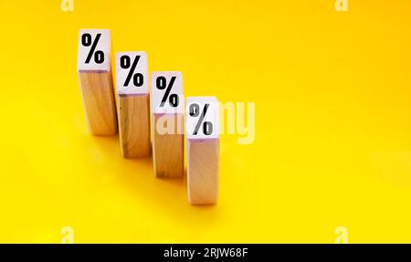 Blocchi di legno con segno di percentuale su sfondo giallo Foto Stock