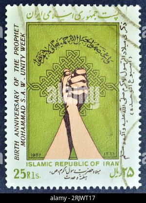 Cancelled postage stamp printed by Iran, that shows Mohammad's Birthday: Inscription, Ornaments, Clasped Hands, circa 1987. Stock Photo