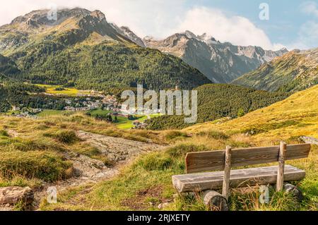 Panchina solitaria con vista su Maloja in primavera, alta Engadina, Grigioni, Svizzera Foto Stock