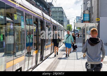 People on a Luas tram station platform boarding a tram in Dublin, Ireland. Stock Photo