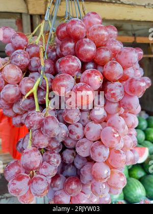 Grappoli freschi di uva rossa sono appesi al negozio di frutta Foto Stock