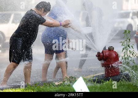 (230824) -- CHICAGO, Aug. 24, 2023 (Xinhua) -- Kids and adults cool off beside an open fire hydrant in the New City neighborhood on the southwest side of Chicago, the United States, on Aug. 23, 2023. The temperature at O'Hare International Airport in Chicago, the third most populous city in the United States, reached 98 degrees Fahrenheit (36.67 degrees Celsius) Wednesday afternoon, breaking the city's previous daily high temperature record for Aug. 23 of 97 degrees Fahrenheit (36.11 degrees Celsius), according to the U.S. National Weather Service. The previous record for Aug. 23 was set in Stock Photo