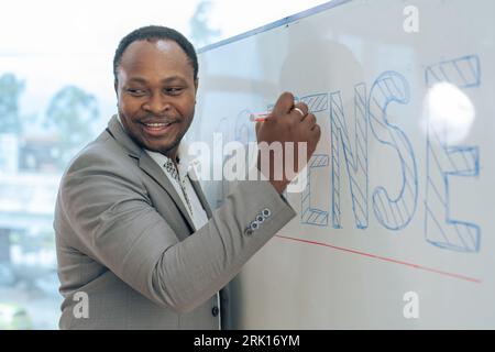 Professore africano di calcolo maschile sta scrivendo sulla lavagna bianca in classe Foto Stock