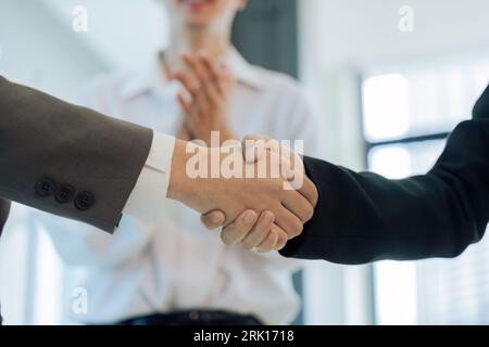 uomini d'affari professionisti di successo in costume formale che stringono la mano salutando e colleghi che battono le mani nell'ufficio dell'azienda Foto Stock