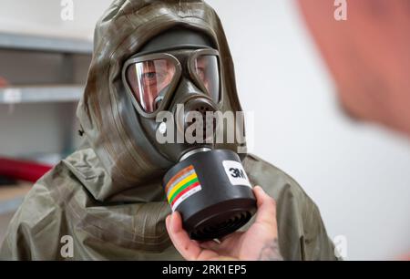 PRODUCTION - 23 August 2023, Lower Saxony, Dethlingen: Workers check their protective extractions during a demonstration. Chemical weapons originating from the Wehrmacht are now to be recovered from the Dethlingen pond. The pond was filled in after the Second World War. More than 100,000 different weapons are said to be in the pond, which is ten to twelve meters deep. An investigation of a neighboring groundwater body had revealed massive contamination with explosive ordnance degradation products. During the subsequent reconnaissance of the pond between September 2019 and April 2020 at three p Stock Photo